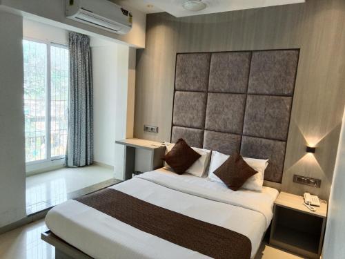 a bedroom with a large bed with a large headboard at Hotel Preston Inn in Mumbai