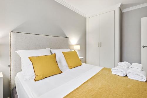 een wit bed met gele kussens en handdoeken erop bij Apt 1B LuxuryRentalsMurcia in Murcia