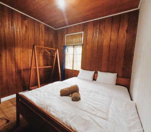 een slaapkamer met een bed met een houten muur bij Likat Surf House in Tua Pejat