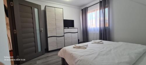 a bedroom with a white bed and a television at Casa Alex in Gălăuţaş