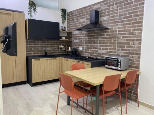 a kitchen with a wooden table and a brick wall at Casa Ma Pì - relax e comfort nel centro di Augusta in Augusta