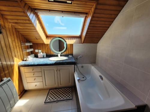 une salle de bain avec une baignoire, un lavabo et un miroir dans l'établissement Maison de la dune, vue mer et accès plage direct, à Plouescat