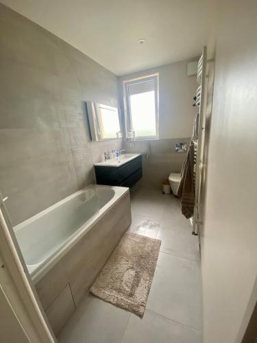 une salle de bain blanche avec une baignoire et un lavabo dans l'établissement Agréable maison proche 24h circuit et centre ville Pleasant house near circuit and city center, au Mans