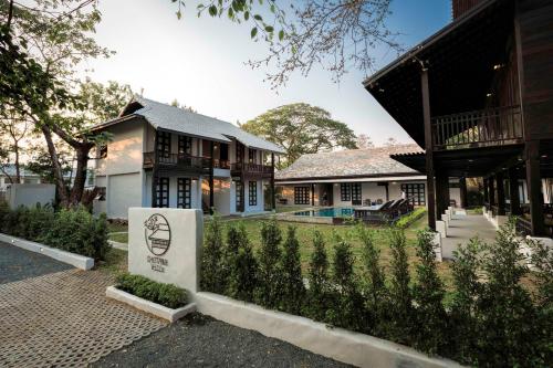 a house with a sign in front of a yard at Chotana Villa Hotel Chiang Mai in Chiang Mai