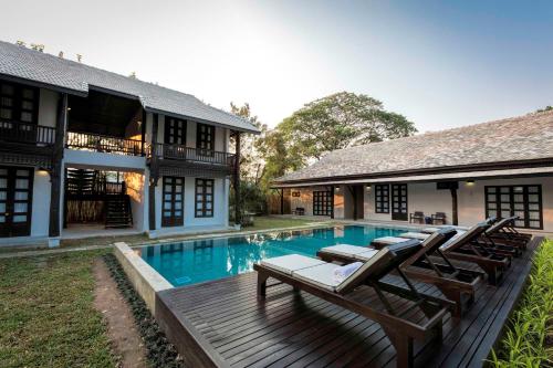 a swimming pool with lounge chairs and a house at Chotana Villa Hotel Chiang Mai in Chiang Mai