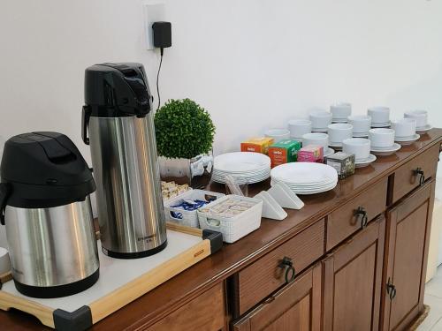 a counter with a coffee maker and plates and cups at Pousada Araúna Angra in Angra dos Reis