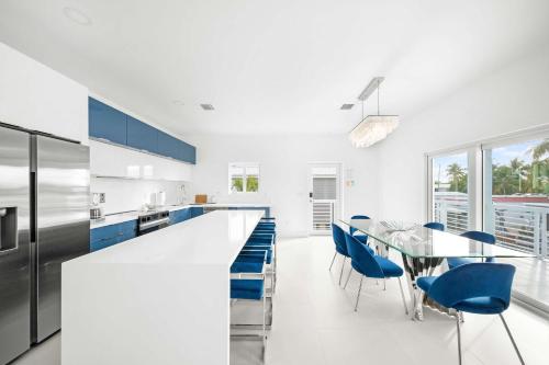 a white kitchen with a table and blue chairs at Azul Paradise - Waterfront - Heated Pool - Dock in Marathon