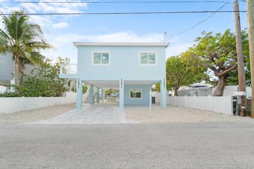 a house on the beach with a white fence at Azul Paradise - Waterfront - Heated Pool - Dock in Marathon