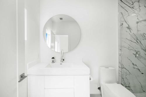 a white bathroom with a sink and a mirror at Azul Paradise - Waterfront - Heated Pool - Dock in Marathon