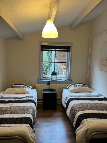 two beds in a room with a window at Vakantiebungalow 95 in Baarland in Baarland