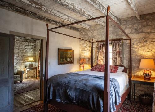 1 dormitorio con cama con dosel y pared de piedra en Charming 2BR Getaway Near Fredericksburgs Best Wineries, en Fredericksburg