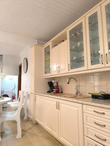 a kitchen with white cabinets and a table and chairs at Poseidon Apartments in Gaios