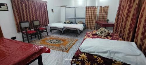 a room with two beds and a table and chairs at Ashirwad Home Stay in Allahābād
