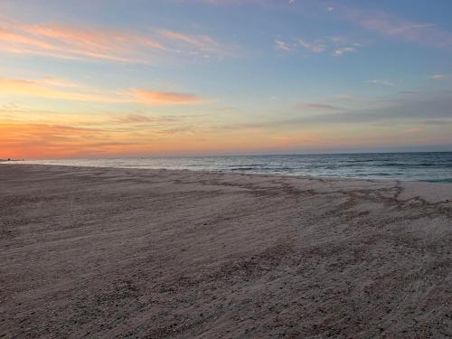 a beach at sunset with the ocean in the background at Charming Condo Steps from the Beach & Lagoon! in Gulf Shores