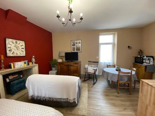 a living room with a table and a clock on the wall at Studio Logis les Roses in Bourbon-lʼArchambault