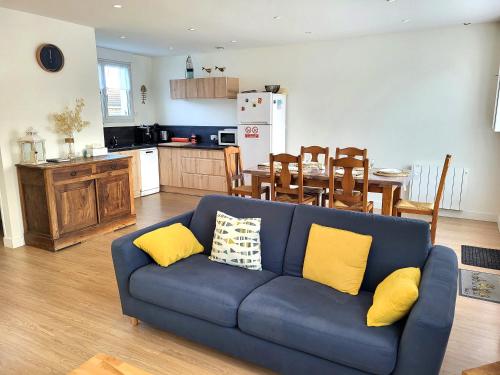 ein Wohnzimmer mit einem blauen Sofa und gelben Kissen in der Unterkunft La villa Kikifil, bord de mer in Saint-Germain-sur-Ay