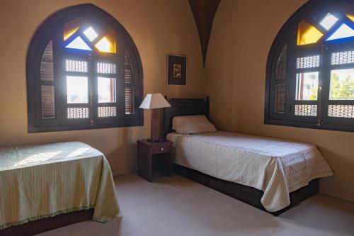 a bedroom with two beds and two windows at Laziza in Luxor