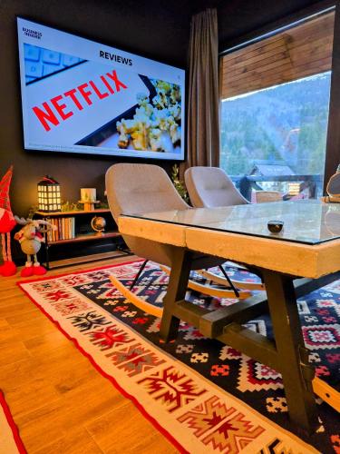 a living room with a television and a table and chairs at Vila Ferdinand Apartments in Sinaia