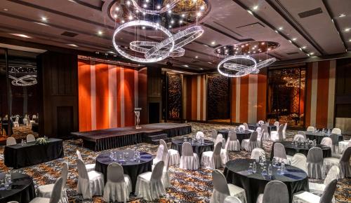 a banquet hall with tables and chairs and chandeliers at Hilton Petaling Jaya in Petaling Jaya