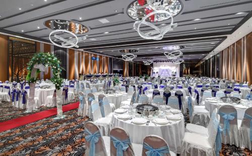 a banquet hall with white tables and chairs and chandeliers at Hilton Petaling Jaya in Petaling Jaya