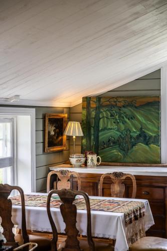 a dining room with a table and a painting on the wall at Cozy guest house in the countryside in Håltebyn