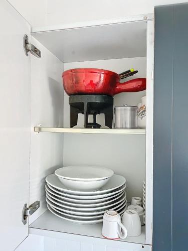 une armoire avec une pile de assiettes et un bol rouge dans l'établissement Situation et vue exceptionnelles 338L ROLL, à Cannes