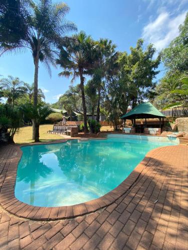 a large swimming pool with palm trees in the background at The Ultimate Lodge in Louis Trichardt