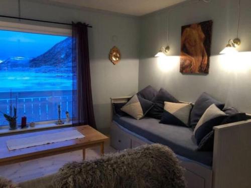 a living room with a couch and a large window at Charming house in fjord Lofoten in Slydalen
