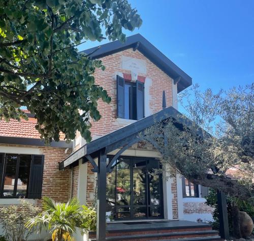 une maison en briques avec une grande fenêtre et un porche dans l'établissement VILLA DE PRESTIGE avec salle de sports privée, à Gujan-Mestras