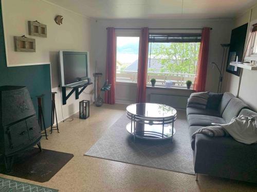 a living room with a couch and a table at Leilighet med balkong og havutsikt på Napp. in Napp