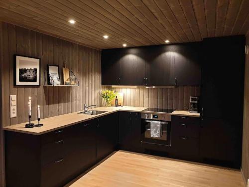 a kitchen with black cabinets and a sink at Magic views and walking distance to best beaches in Leknes