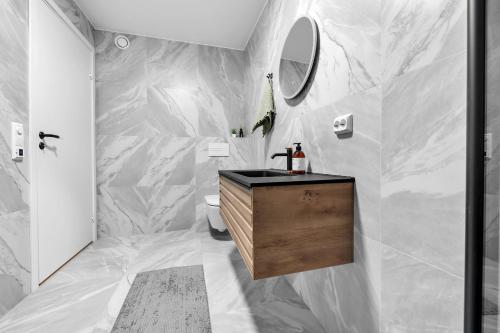 a bathroom with white marble walls and a sink at Northstay - The Urban City Haven in Tromsø