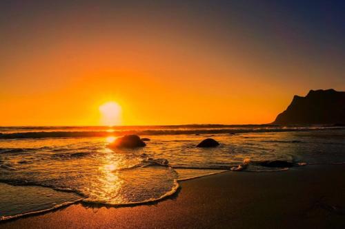 a sunset on the beach with the sun setting at Nora's Waterfront Cabin in Svolvær