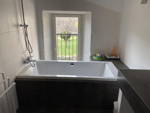 une grande baignoire dans une salle de bain avec une fenêtre dans l'établissement La Pauze - Gîte familial au bord de l'Allier - Family Cottage by Allier Riverside, à Villeneuve-dʼAllier