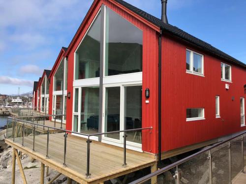 a red house with glass windows on a dock at Fisherman`s Cabin Lofoten in Ballstad