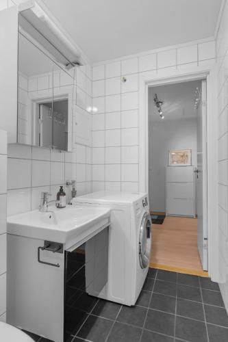 a white kitchen with a sink and a washing machine at Modern loft apartment in Tromsø City Center in Tromsø