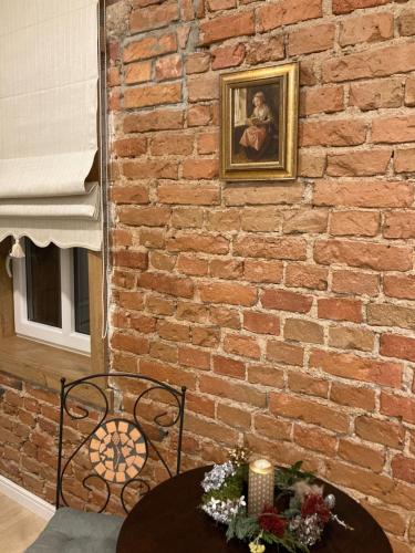 a brick wall with a table with a picture on it at Apartamentai Domus Antiqua in Zarasai