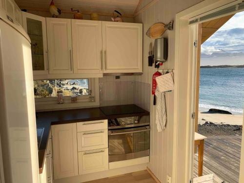 una cucina con mobili bianchi e vista sull'oceano di Lofotparadis - nydelig hytte på unikt sted a Valberg