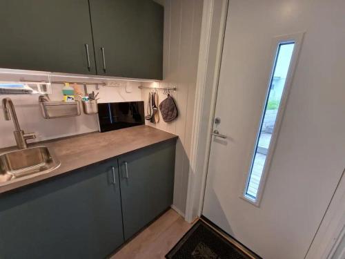a kitchen with a sink and a door with a window at Panoramic seaview cabin for two persons by the sea in Hovdan