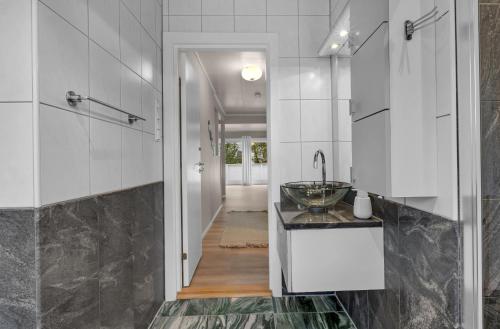 a white bathroom with a sink and a hallway at Northstay - Grimsby House in Tromsø