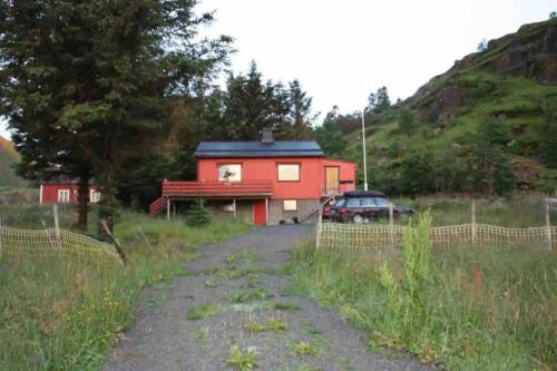 a red house with a car parked in front of it at Northern Light Cabin Lofoten in Sennesvik