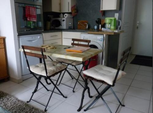 une cuisine avec une table et des chaises dans une cuisine dans l'établissement Appartement cosy à Saint-Mamet - 36 m² - Vue montagne, à Saint-Mamet
