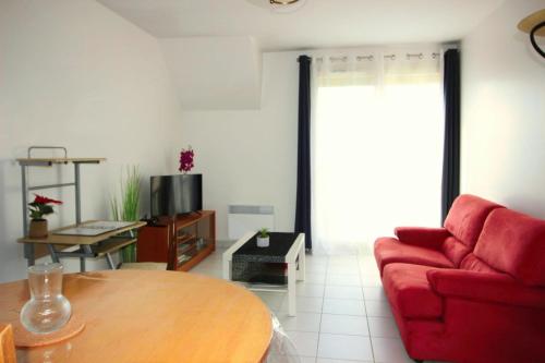 a living room with a red couch and a table at Comme à la maison entre Fontainebleau et Moret sur Loing in Champagne-sur-Seine