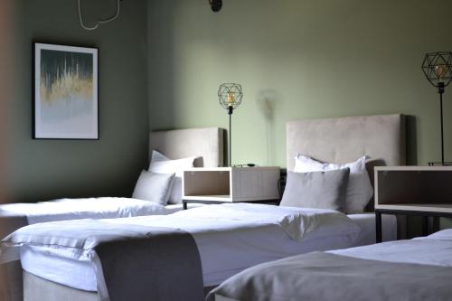 three beds in a room with white sheets and pillows at Hotel Pamela Concept in Negotino
