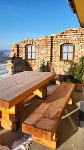 a wooden picnic table in front of a brick wall at Dom na Ubocy in Groń