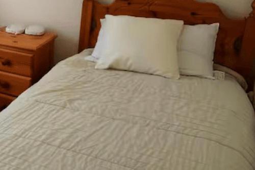 a white bed with two pillows and a night stand at 3BedHouse-Ballyliffin-NearBeach-GolfCourses nearby in Ballyliffin