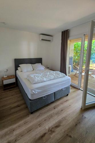 une chambre avec un lit et une porte coulissante en verre dans l'établissement Fiori Di Cala Rossa, Établissement CARDOGA Piscine, Mer & Montagne, à Lecci