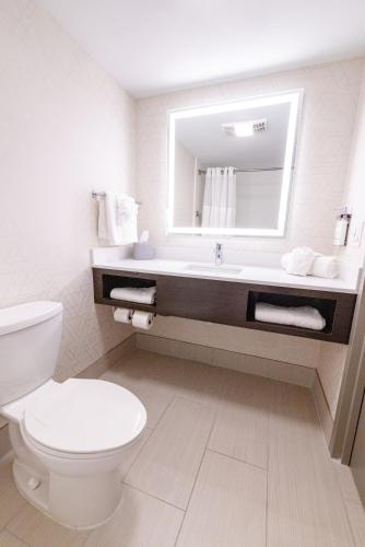 a bathroom with a toilet and a sink with a mirror at Holiday Inn Express - Neptune by IHG in Neptune City