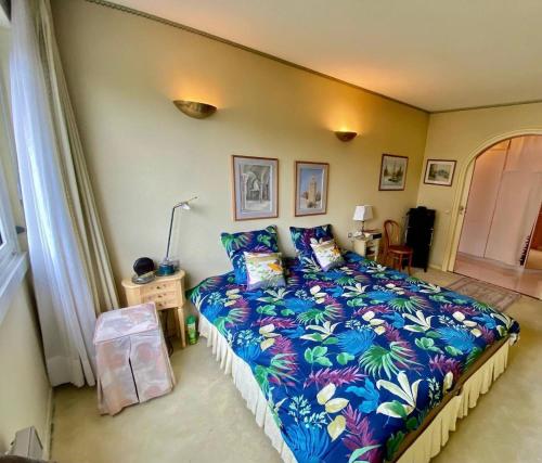 une chambre avec un grand lit avec une couverture colorée dans l'établissement Appartement T3 bis aux portes de Genève, à Annemasse