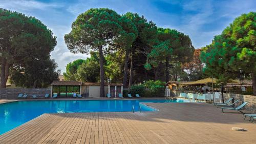 a swimming pool with chairs and trees in the background at Fiori Di Cala Rossa, Établissement CARDOGA Piscine, Mer & Montagne in Lecci